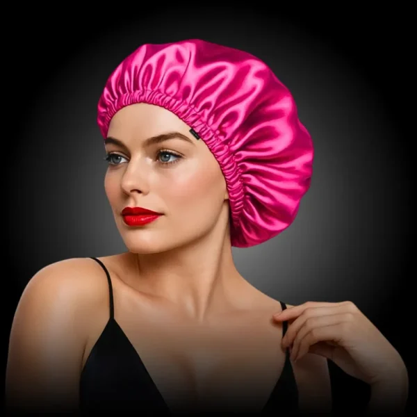 Mulher usando touca de cetim rosa pink da marca ZERO FRIZZ, com lábios vermelhos e expressão elegante.